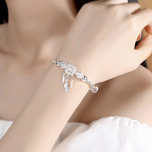 Silver dreamcatcher feather charm bracelet on woman wrist for elegant summer styling