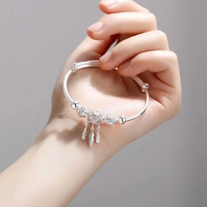 Silver adjustable dreamcatcher feather bangle with镂空 beads shown on a hand