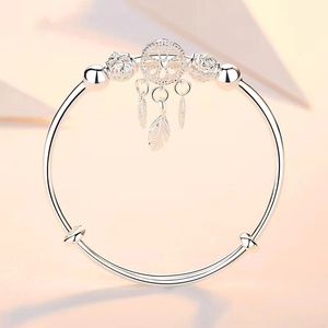 Silver dreamcatcher bangle featuring feather charms and polished open cuff design