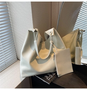 Détail du grand sac hobo blanc et de sa pochette assortie en cuir grainé sur table