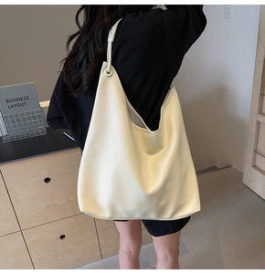 Detailed view of large off-white hobo bag with pebble leather texture on a model
