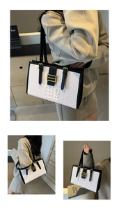 Detail of white crocodile pattern tote bag with black handles and gold hardware
