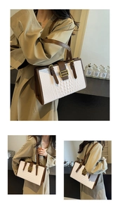 Detail view of white crocodile pattern tote with dark brown trim and gold metal clasp