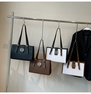 Detail of four crocodile embossed tote bags with gold H-buckles in assorted colors