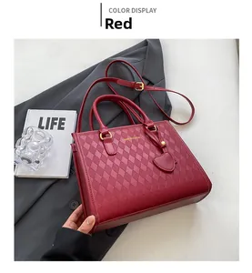 Detail of red quilted leather tote bag with gold logo and heart charm pendant