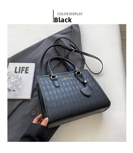 Detail of black quilted leather tote bag with gold hardware and heart-shaped charm