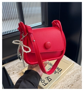 Close-up of red lychee pattern leather saddle bag with pearl bow and heart charms