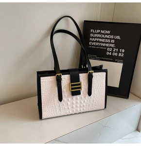 Detail view of white crocodile pattern leather and black contrast panels with gold hardware