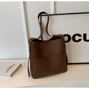 Detailansicht der dunkelbraunen Eimertasche aus genarbtem Leder mit Tasche und Knopf