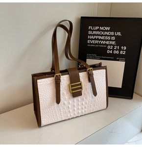 Detail of white crocodile embossed leather and brown trim on a stylish tote bag
