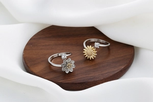 Macro detail of rotating sunflower and silver flower open rings with zirconia stones