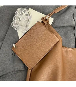 Détail du sac cabas marron à motif litchi avec pochette zippée assortie sur tissu gris