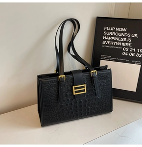 Detailed close-up of black crocodile texture and golden hardware on large tote bag