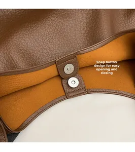 Détail du fermoir magnétique argenté sur sac cabas en cuir marron avec doublure orange
