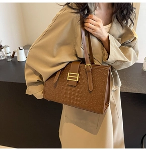 Detail of caramel crocodile embossed leather tote bag with elegant gold buckle