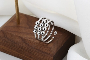 Detail eines silbernen Anti-Angst-Rings mit zehn drehbaren Perlen auf Holzsockel