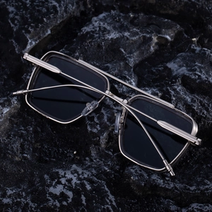 Macro shot of silver square metal frame sunglasses on dark rock texture surface