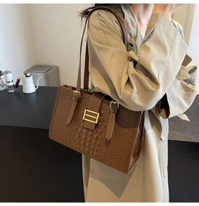 Brown crocodile texture shoulder bag styled with a minimalist beige trench coat