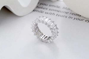 Gros plan d'une bague éternité en argent avec diamants baguette sur fond blanc épuré
