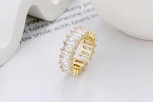 Détail macro d'une bague ouverte dorée ornée de zircons rectangulaires taille baguette