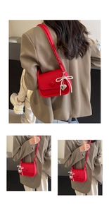 Close-up of red lychee leather saddle bag with pearl bow and silver heart charm