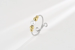 Detail of adjustable open ring featuring gold beads and a white pearl on silver band
