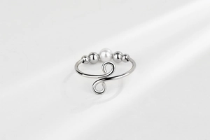 Detailed view of silver adjustable ring with white pearl and rotating stress relief beads