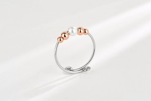 Detail view of adjustable ring with rose gold beads and elegant white pearl decoration
