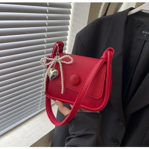 Detail of red lychee pattern saddle bag with pearl bow and silver heart pendant
