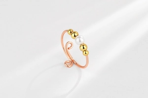 Detail of rose gold spinning bead ring featuring a white pearl and spiral texture