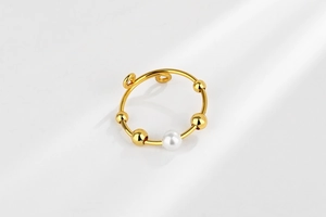 Close-up of golden anxiety relief ring with sliding beads and a white pearl accent