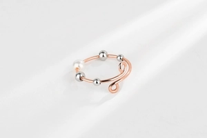 Detail of anxiety ring with spinning silver beads and pearl on rose gold open band