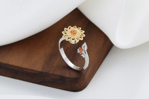 Detail of adjustable sunflower ring featuring orange zircons on a rustic wood stand