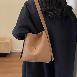 Minimalistische braune Beuteltasche aus Leder kombiniert mit einem marineblauen Mantel