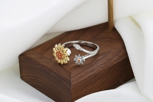 Detailed close-up of a silver sunflower rotating ring with golden accents and orange gems