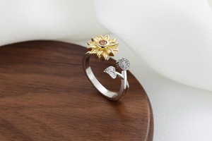 Close-up of rotatable sunflower ring with yellow gemstone and pavé leaf on wooden base