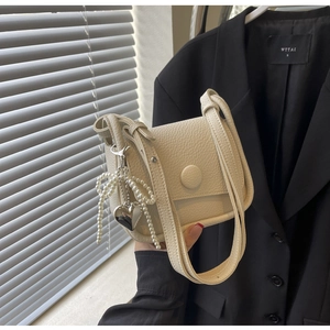 Detail view of lychee leather saddle bag with pearl bow and silver heart pendant