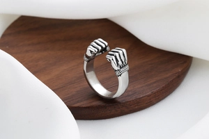 Detail of vintage silver clenched fist ring with antique finish on a wooden stand