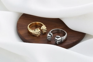 Macro shot of silver and gold boxing glove fist rings on wood with white silk