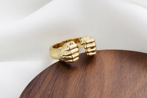 Macro shot of gold-plated fist-shaped open ring showing intricate fist detailing and texture