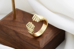 Detailed view of golden double fist power ring on a dark wood pedestal background