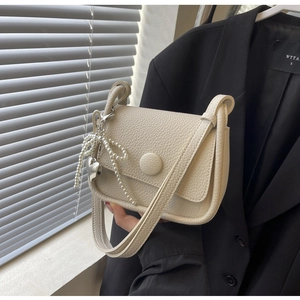 Close-up of lychee textured cream white crossbody bag with pearl bow and heart charm