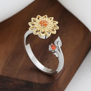Rotating sunflower spinner ring with orange crystals and leaf detail on wood surface