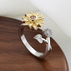 Rotating sunflower open ring with golden petals and amber zircon on a rustic wooden background