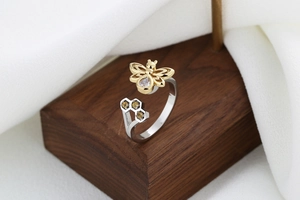 Detail of bee and honeycomb open ring with zircons on a textured wooden base