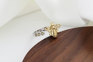 Close-up of a honeycomb ring with a golden bee and yellow zircons on white fabric