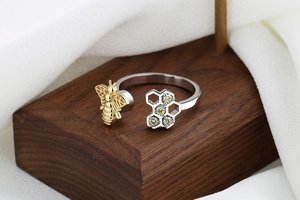 Detailed macro view of the gold bee and silver honeycomb pattern on the open ring