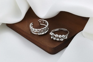 Close-up of double-layer silver spinning chain rings with rotating beads on wood