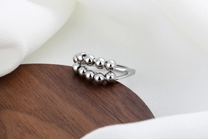 Macro detail of silver double-layered rotatable bead chain ring on a wooden stand