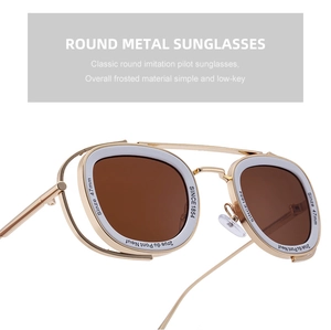 Macro view of gold metal round sunglasses featuring white decorative rings and engravings